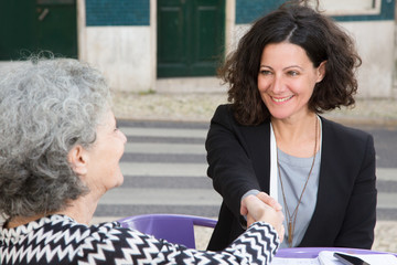 Senior lady meeting with young consultant in cafe. Smiling women handshaking. Greeting or...