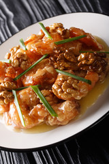 Deep-fried Chinese shrimps with caramelized walnuts and spring onions close-up. vertical