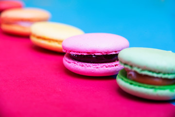 Tasty different colored macarons on multicolored background
