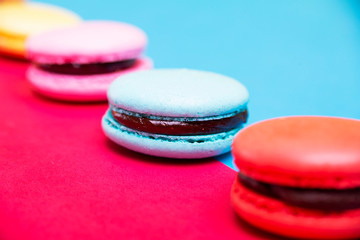 Tasty different colored macarons on multicolored background