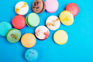 Tasty different colored macarons on blue background