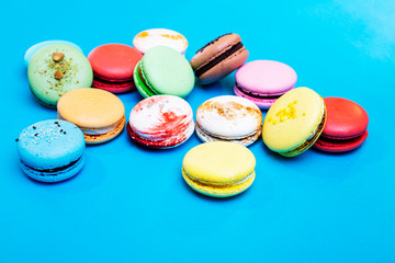 Tasty different colored macarons on blue background