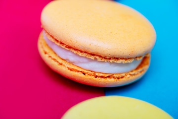 Tasty different colored macarons on multicolored background