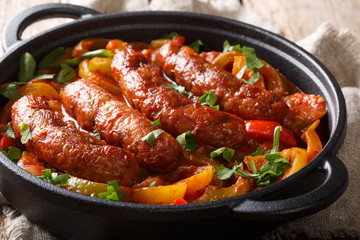 Grilled sausage main course with roasted peppers, onions and tomatoes closeup in a frying pan. horizontal