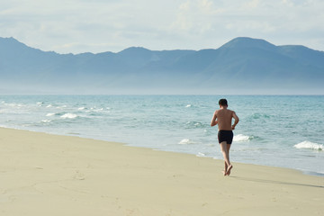 A man performs a morning workout. Running along the sandy beach along the coastline. Copy space for text. Vietnam