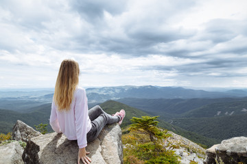 Naklejka premium Extreme trip. At the edge of an abyss sitting in the clouds. The hills are below . Awesome nature 