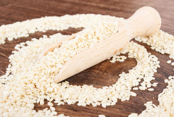 Sesame seeds with wooden spoon on board