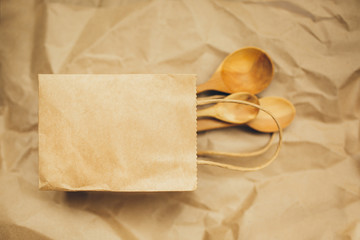 Paper packages with wooden spoons on brown background. Copy space. Top view. Eco and save earth concept. Zero waste.