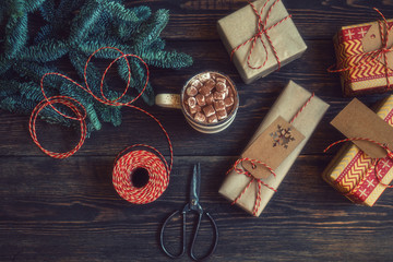 Christmas background with cup coffee and gift boxes on rustic wooden board. Presents, decoration and twine ribbon. Luxury New Year or Christmas gift. Preparation for the holidays. Toned image.
