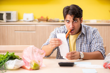 Young man calculating expences for vegetables in kitchen 