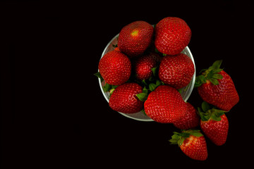 Fresh red big strawberries in a glass bowl on a black background. The high content of manganese. Fresh and healthy fruit. Wonderful strawberries.