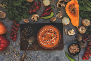 Pumpkin soup in a bowl with autumn vegetables and pumpkin seeds. Vegan soup. Vegetables cream soup and ingredients. Top view. Concept of healthy eating or vegetarian food. Top view with copy space.