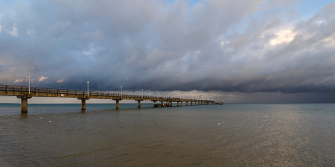 Fototapeta premium Sea bridge at the Baltic Sea against a dramatic sky with clouds 