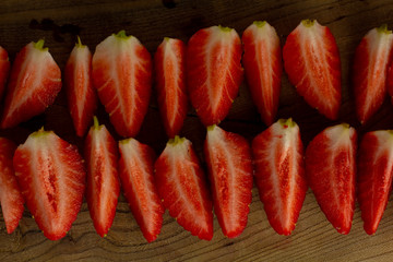Fresh red strawberries cut into slices on a wooden cutting board. Pieces of strawberries. Delicious sliced fruit.