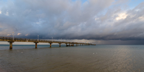 Fototapeta premium Sea bridge at the Baltic Sea against a dramatic sky with clouds 