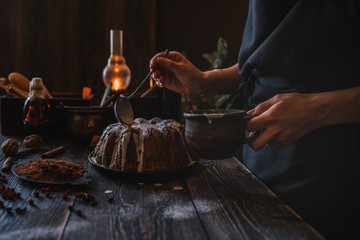 Cooking homemade cake Christmas Eve at home rustic kitchen. Woman's hands make pudding. Ingredients for cooking christmas baking on dark wooden table. Merry Christmas and Happy Holidays! Toned image.