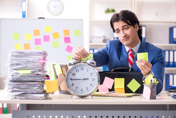 Young male handsome employee in conflicting priorities concept 