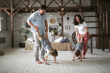 Parents hold children by foot, boys walk on hands