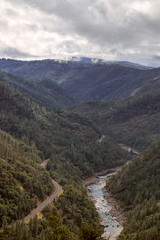 Aerial view of the Feather River Canyon and railroad tracks with storm clouds passing overhead in the sky.