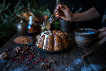 Holiday cake on wooden table with berry, spice and chocolate at rustic home kitchen. Christmas baking background. Ingredients for cooking on dark wooden background. Homemade festive food. Toned image
