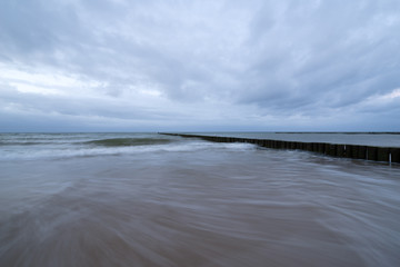 Sunset on the beach with waves against a dramatic blue cloudy sky, baltic sea, Usedom, Germany