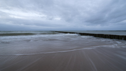 Sunset on the beach with waves against a dramatic blue cloudy sky, baltic sea, Usedom, Germany