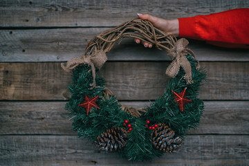 Christmas wreath on female hands. Girl holding a handmade christmas wreath. Seasonal holidays, rustic theme, adorning. Christmas decor. Winter holidays tradition concept. Toned image.