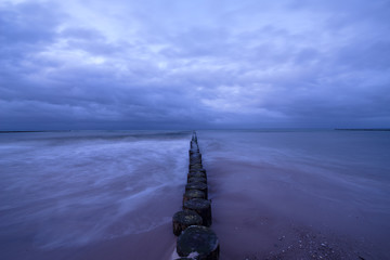 Sunset on the beach with waves against a dramatic blue cloudy sky, baltic sea, Usedom