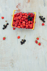 Mini shopping basket full of fresh red ripe raspberry and blackberry on vintage background