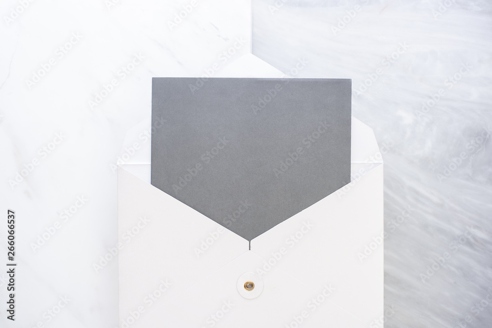 Poster Top view of blank grey card in white envelop on two layer step of marble table top.Mock up template for display of design.business items.