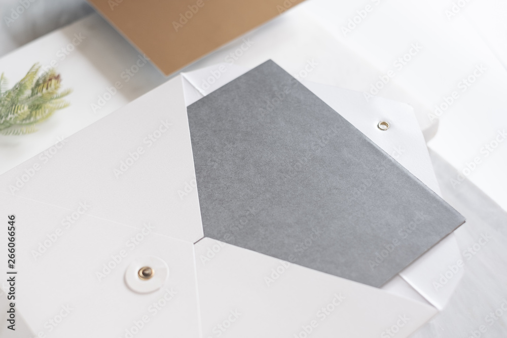 Poster top perspective view of blank grey card in white envelop with pine leaf on two layer step of marble table top.Mock up template for display of design,modern business items.