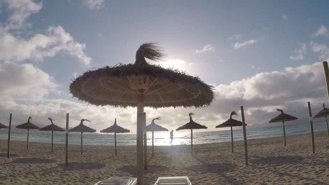 vistas de unas sombrillas de playa con el sol sobre el horizonte en una playa de  mallorca