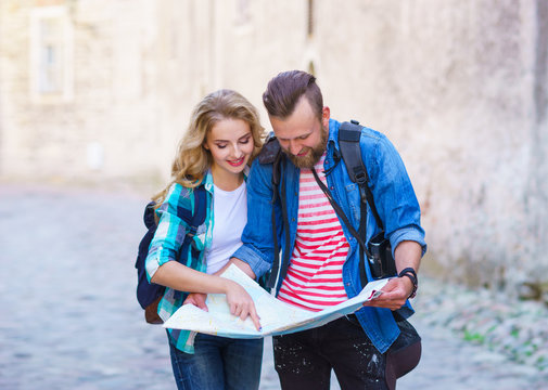 Young travelers with a tourist map. Man and woman having vacation. Backpackers, traveling and tourism concept.
