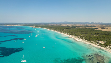 Amazing drone aerial landscape of the charming beach Es Trencs and the boats with a turquoise sea. It has earned the reputation of Caribbean beach of Mallorca. Spain