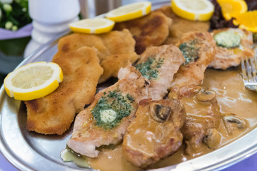 Schnitzelplatte mit Zitronenscheiben und Kräuterbutter