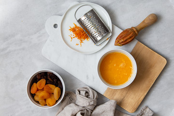 Fresh Orange Juice and Peel, raisins, dried apricots, almonds on marble backround with copy space