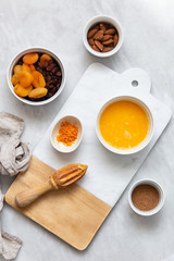 Fresh Orange Juice and Peel, raisins, dried apricots, almonds on marble backround with copy space