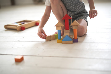 lonely boy plays wooden constructor on the floor