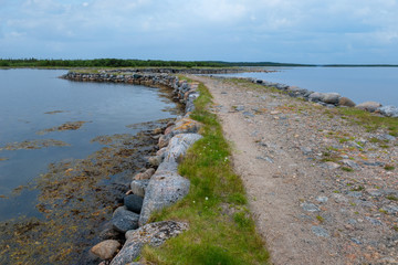 Fototapeta na wymiar Big Solovetsky dam connecting the island the Big Solovetsky island with large Muksalma. Length 1200 meters, base width 7 meters