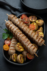 Close-up of bbq chicken kabobs with mini potatoes and cherry tomatoes, vertical shot
