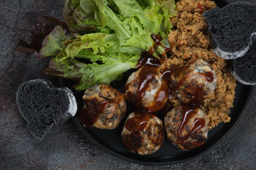Top view of fried mushrooms and cheese truffles, couscous, fresh salad leaves and black baguette