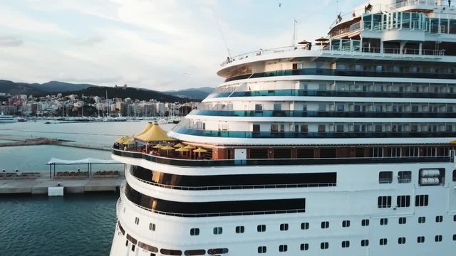 Close up of the cruise liner back with cabins and big sun umbrellas on board, travel and resort concept. Stock. Cruise ship at the sea port with white yachts, mountain and coastal city.
