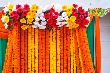 strings of marigold flower with colorful daisies as background at a wedding and engagement function.