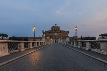 Castle Sant Angelo with the Aurelius bridge in the morning at dusk. Stone bridge with historical figures and lighting over river Tiber without people and with clouds in the sky