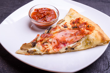 A slice of pizza with cheese, ham and mushrooms on white platter 