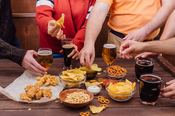 Hands of friends holding beer glasses drinking together