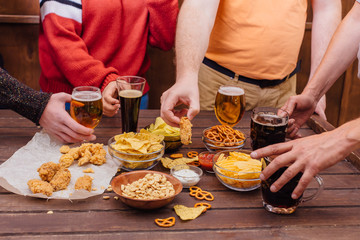 Hands of friends holding beer glasses drinking together