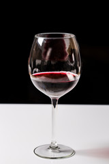 Red wine on a wineglass over a dark solid black background