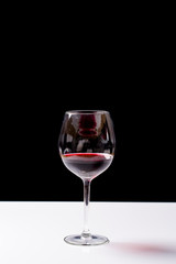 Red wine on a wineglass over a dark solid black background
