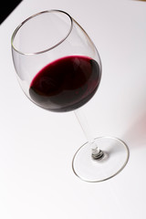 Red wine on a wineglass on a white background close up still